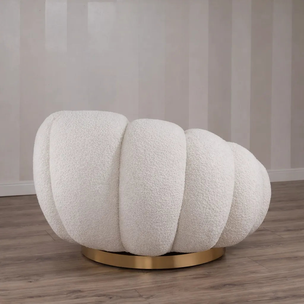 Poltrona Elodia in tessuto bouclé color panna con seduta avvolgente e base circolare in metallo color oro