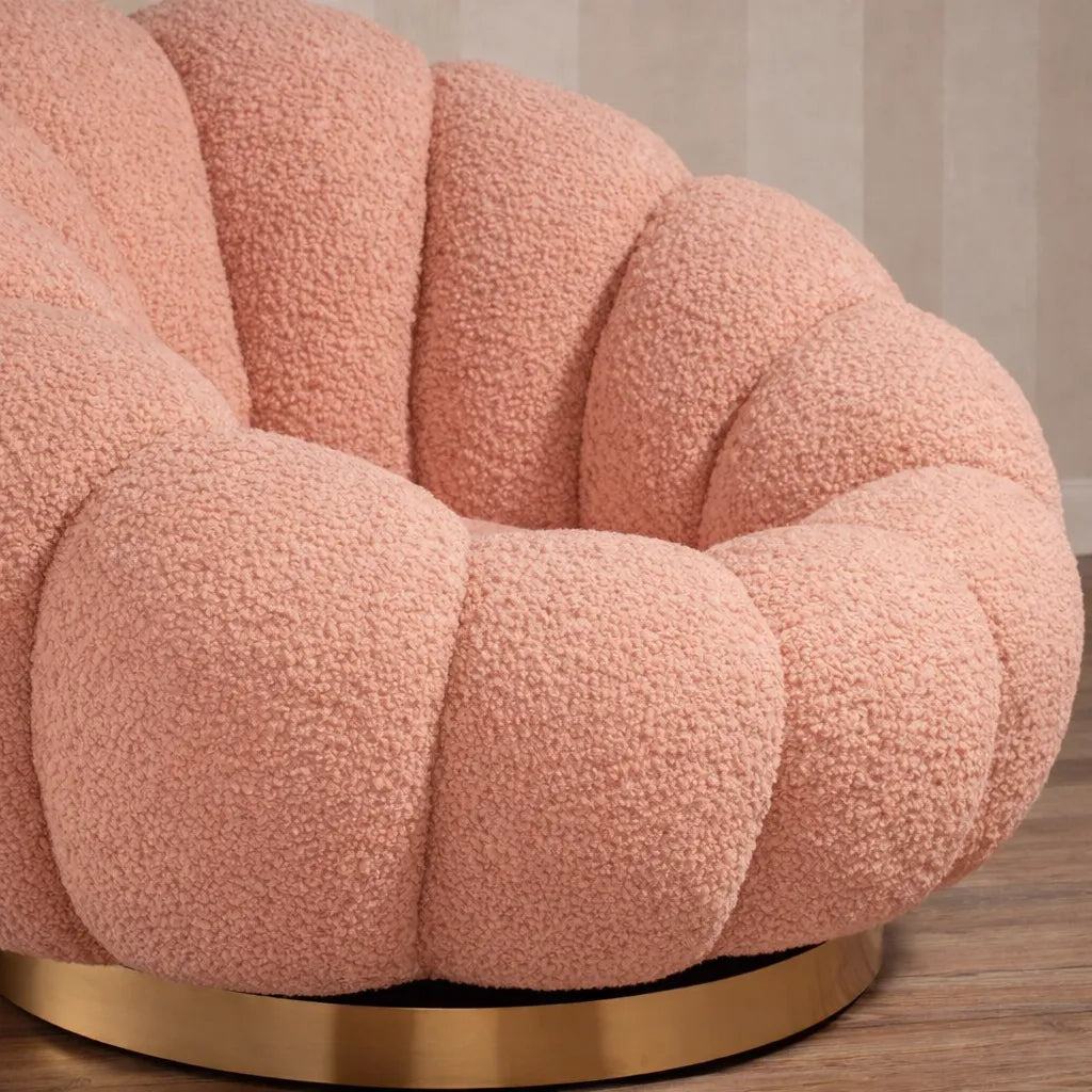 Poltrona Elodia in tessuto bouclé color rosa con seduta avvolgente e base circolare in metallo color oro