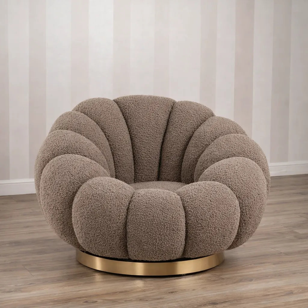 Poltrona Elodia in tessuto bouclé color tortora con seduta avvolgente e base circolare in metallo color oro