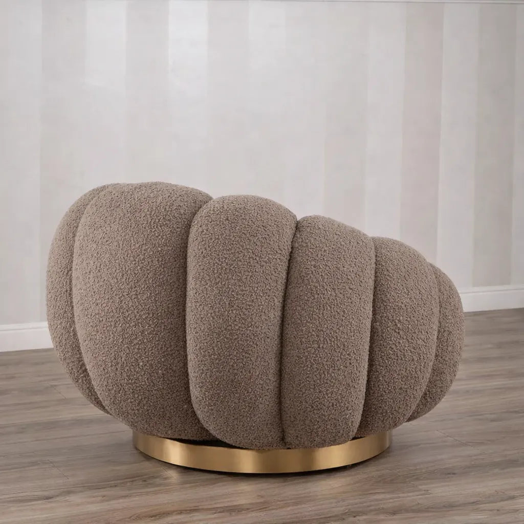 Poltrona Elodia in tessuto bouclé color tortora con seduta avvolgente e base circolare in metallo color oro