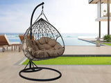 Poltrona sospesa Lita XL a uovo in rattan intrecciato con struttura in acciaio verniciato e cuscini grigi. Dondolo elegante per giardino e interni.