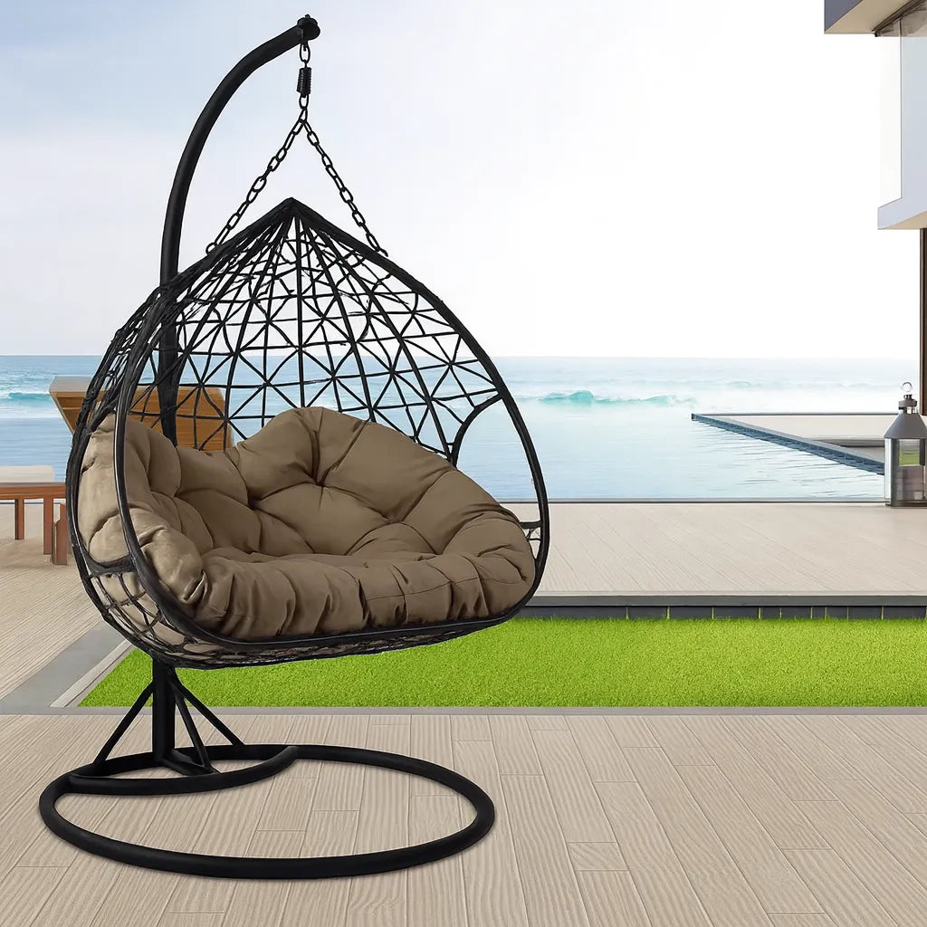 Poltrona sospesa Lita XL a uovo in rattan intrecciato con struttura in acciaio verniciato e cuscini grigi. Dondolo elegante per giardino e interni.
