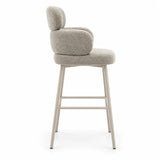 Sgabello Alma in tessuto tortora con seduta e schienale imbottiti, struttura in metallo color cashmere e poggiapiedi integrato.