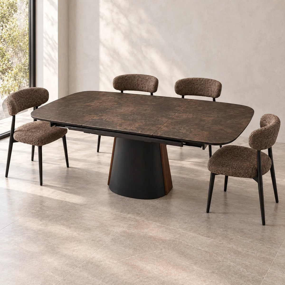 Tavolo Orfeo allungabile 180–230 cm con piano in ceramica marrone grigiato scuro e base in metallo nero con inserto veneer noce scuro.