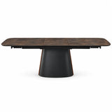 Tavolo Orfeo allungabile 180–230 cm con piano in ceramica marrone grigiato scuro e base in metallo nero con inserto veneer noce scuro.
